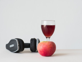 wine apple in glass with black hreadphone on white background, red apple on white table,