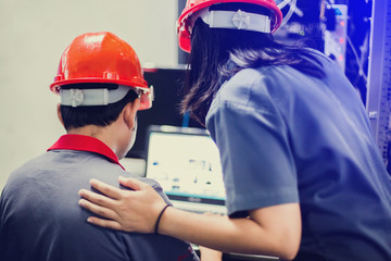 A portrait of an industrial man and woman engineer with laptop in control room of factory.