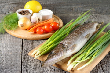 Raw fish on the table among fresh vegetables before cooking.