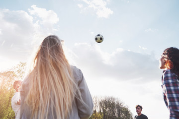 A group of friends in casual outfit play soccer in the open air. People have fun and have fun. Active rest and scenic sunset