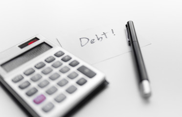 calculator with a pen and paper note with debt word isolated on white background