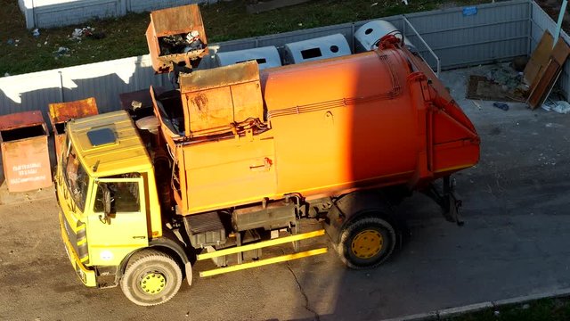 A garbage truck cleans garbage cans in the courtyard of a residential area from garbage and takes it to landfill, garbage removal