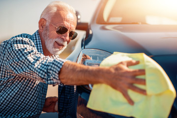 Senior man cleaning his car outdoors