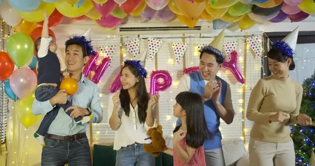 Group of young asian family dancing together in party event at home. Happy family celebrating New Year's Eve.