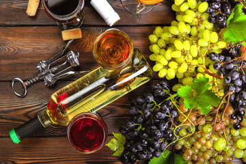 wine with branches of white grapes. On a wooden table.