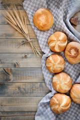 Crusty round bread rolls, known as Kaiser or Vienna rolls scattered on linen towel on rustic wood
