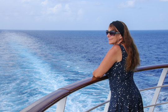 Eine Frau schaut von einem Kreuzfahrtschiff auf das Meer 