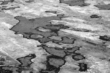 Pavement and snow on its side in black and white.