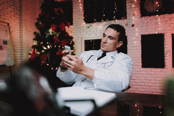 Doctor Using Smartphone in Office on New Year Eve.