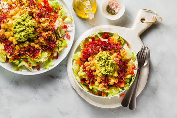 Healthy vegan salad with fresh vegetables, sprouts, avocados and chickpeas in mango juice. Raw food for a healthy family