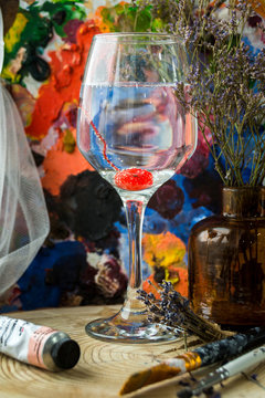 A glass of wine and a cherry at the bottom. Paint background