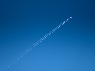 Clear blue sky with condensation trail of aircraft.