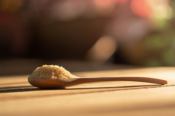 Brown sugar in wooden spoon on table. Blur background.