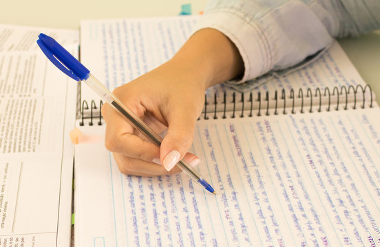 Education and concept. Student studying for a school exam. Female hand writing on notebook and reading.