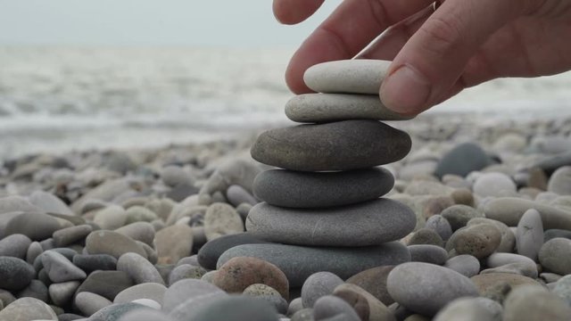Female hand building a stack of stones on the beach