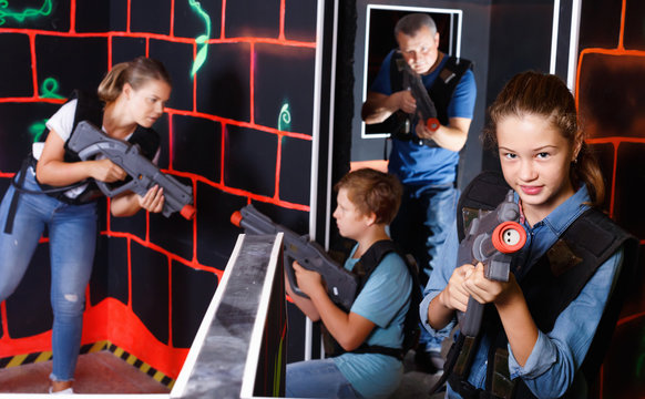 Portrait of teenager girl with laser gun having fun with her family on lasertag arena