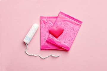 women intimate hygiene products - a pair of sanitary pads and tampon isolated on pink background