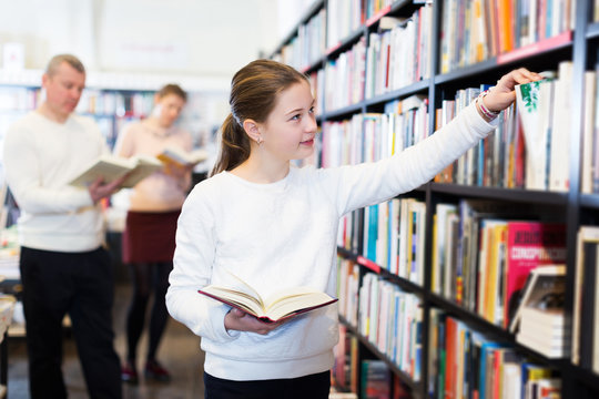 girl searching for textbooks on bookshelves