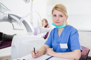 Female stomatologist recording diagnosis