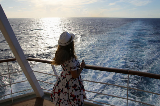 Eine Frau schaut von einem Kreuzfahrtschiff auf das Meer, Sonnenuntergang 