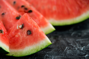 Slices of fresh ripe watermelon on a dark background.