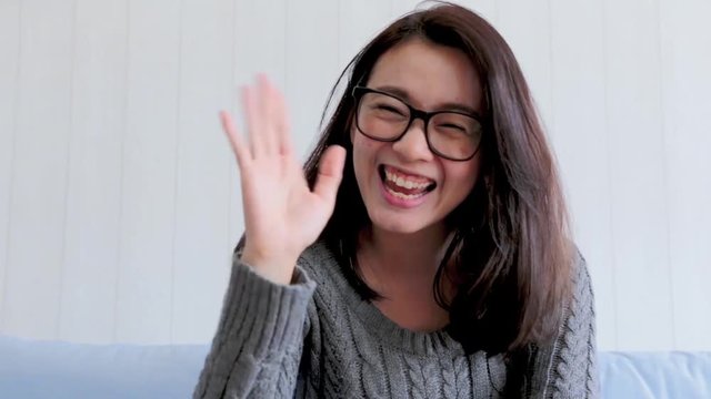 Smiling young asian woman while connection on video call from the point of view of the computer screen