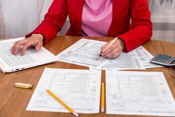 Woman filling 1040 form and typing on laptop