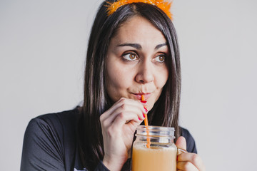 young beautiful woman drinking orange juice. Wearing a black and white skeleton costume. Halloween concept. Indoors