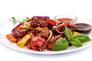Roast Sweet and Sour Pork with vegetables in a plate with sauces, Chinese recipes WOK. Isolated on white background