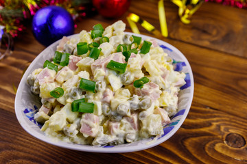 Traditional Russian festive salad Olivier and New Years decorations on wooden table