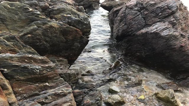 Sea waves break up on the rocks, close-up shot.