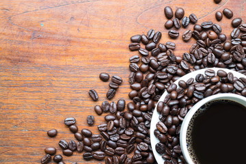Coffee in white cup and coffee beans on wooden table with space for text or image