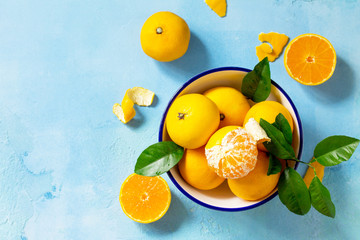 Fresh and juicy tangerines in a bowl on blue a stone or slate background. Seasonal, food background. Top view flat lay background. Copy space.