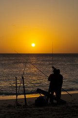 fishermen angler  with rod and reel  in  beach at sunset