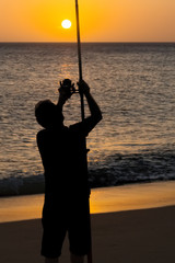 fisherman angler  with rod and reel  in  beach at sunset