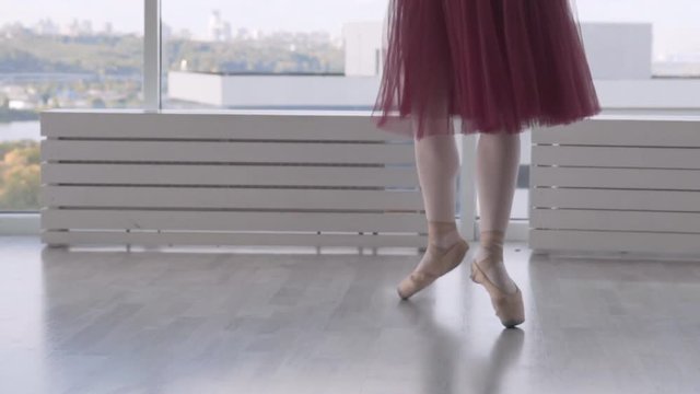 professional-sensual ballerina easily jumps into place in the perithesion class. feet in pointe close up. woman in a long red tutu on tiptoe Slowmotion