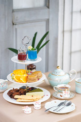 Afternoon tea. Tea party with unicorn macarons, scones, bakeries, pastries and fresh fruits. Selective focus on the earl gray scones