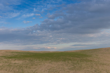 Fototapeta premium Green grass and cracked desert land over dramatic clouds