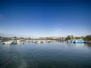Fototapeta na wymiar Port in Mediterranean sea. Sailing boats with a deflated sails near the sea pier.