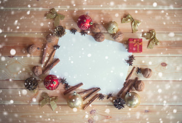 Christmas card with gift, christmas decorations, spices and walnuts on wooden background