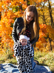 happy young mom with her little newborn daughter in cute pajamas. Walking in autumn Park