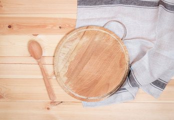 Fototapeta na wymiar Cutting board with wooden spoon and napkin on wooden background. Top view, copy space.