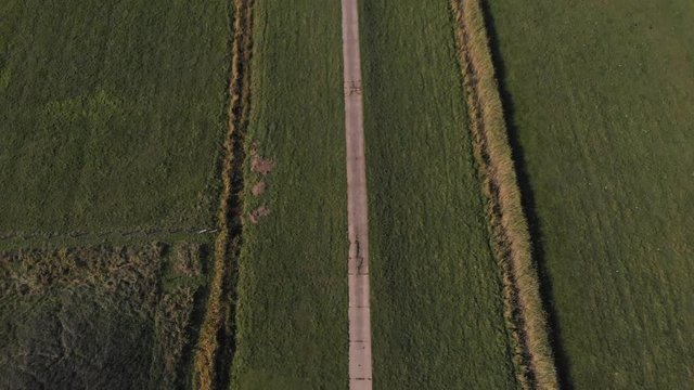 Schwenk &uuml;ber Feldweg zu einem Bauernhof (Luftaufnahme, Drohne)