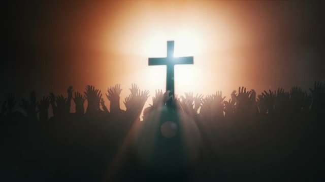 Silhouettes of hands raised in worship with Cross and Dove .
