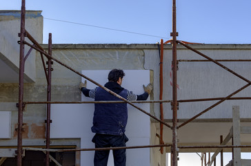 Man working with meter at thermal insulation of the facade.