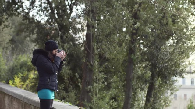 young woman busy taking photographs in a park- slow motion