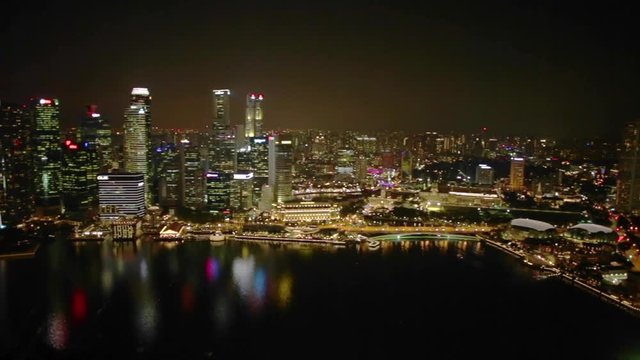 Aerial view of Singapore Marina Bay with Financial District skyscrapers illuminated at night reflected on the harbor. Rooftop above Singapore skyline. Night urban scene.