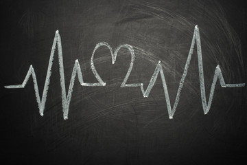 heartbeat chart on blackboard using a pen concept to track healthy lifestyle impulses