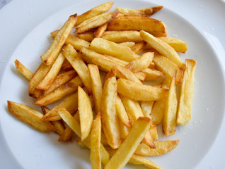 WHITE DISH PLENTY OF GOLDEN CHIPS OR FRENCH FRIES READY TO BE EATEN WITH SALT