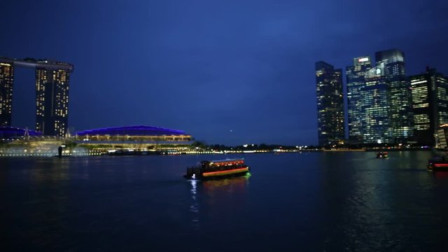 Panorama of marina bay skyline with evening lights reflecting in the sea at blue hour. Singapore cityscape by night. Night scene waterfront.
